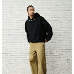 Black hoodie photographed at an angle showing the shoulder piping