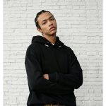Black hoodie styled against a white brick wall