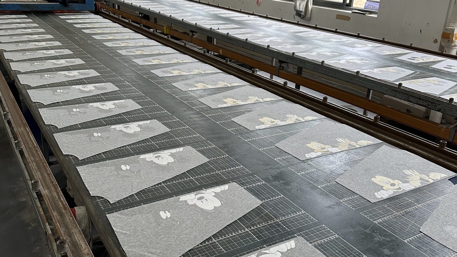 Long drying table holding freshly printed garment panels in the printing department