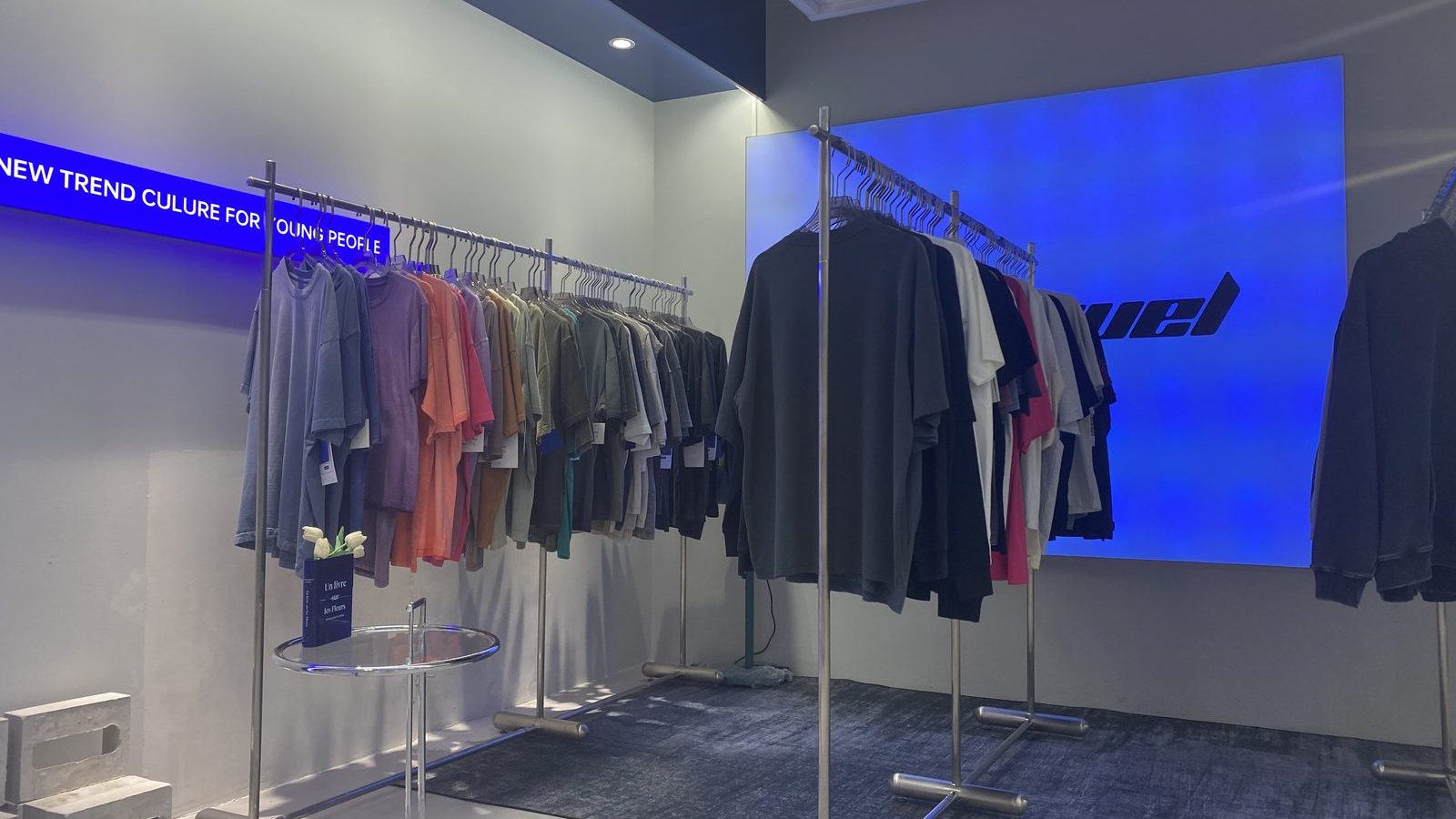 Showroom interior with a blue LED wall and rails of finished garments
