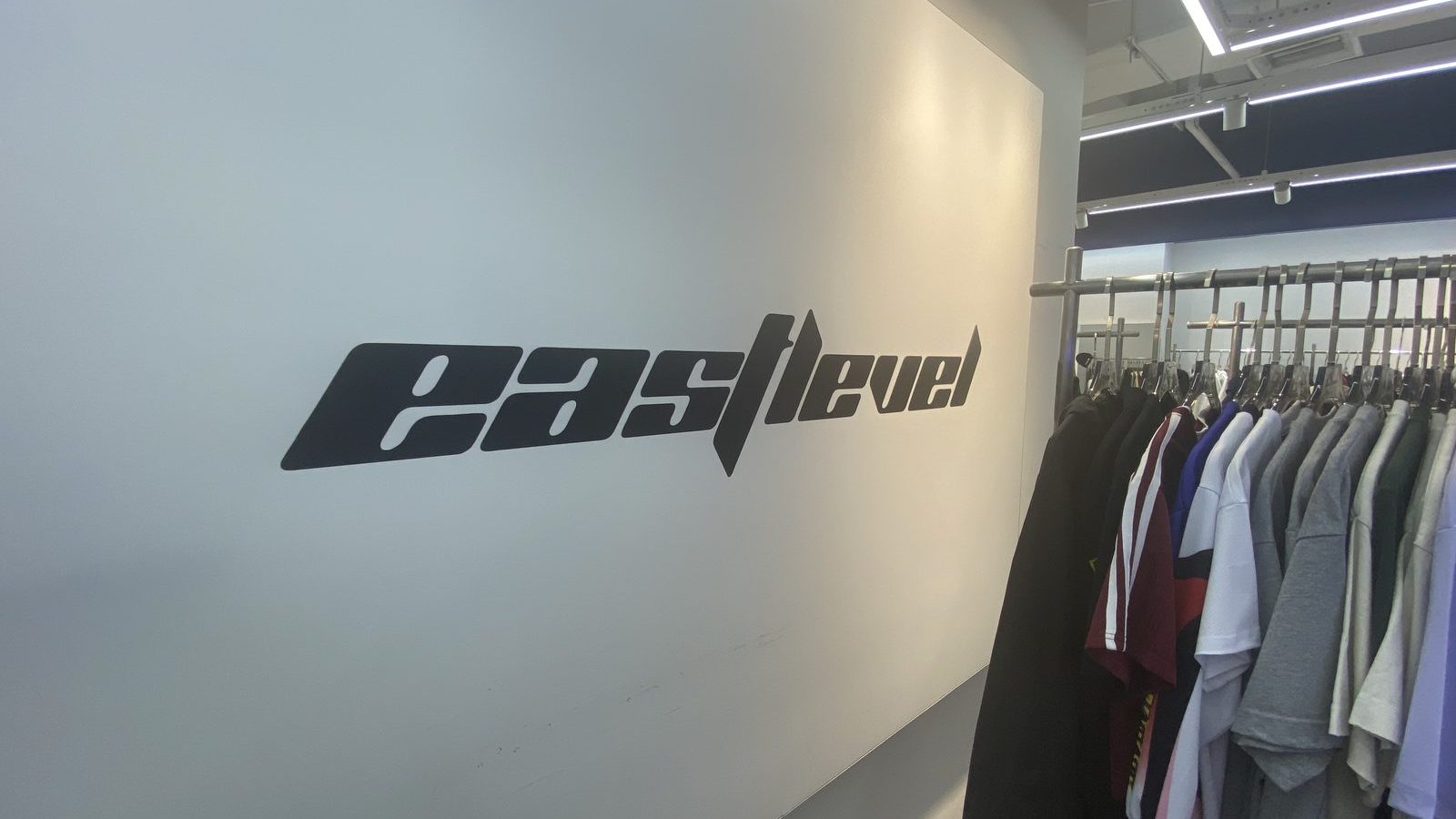 EASTLEVEL logo on the showroom wall next to a rail of hoodies and jackets